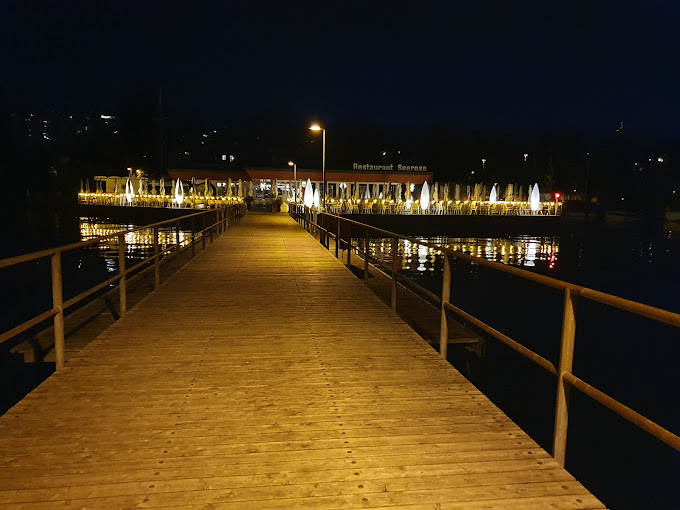 Abendlicher Blick auf den beleuchteten Steg zum Restaurant Seerose in Zürich – stimmungsvolle Kulisse und romantische See-Atmosphäre.