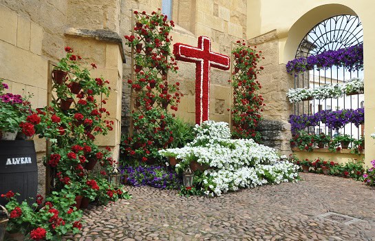 Stimmungsvolles Blumenkreuz in einem traditionellen Innenhof in Córdoba – versteckte Schönheit der Cruces de Mayo im Pfingsten Urlaub entdecken