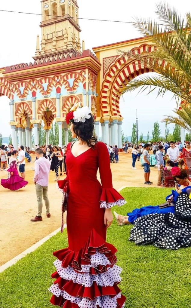 Frau in Flamenco-Kleid vor dem Eingangstor der Feria de Córdoba – festlicher Höhepunkt beim Pfingsten Urlaub in Andalusien